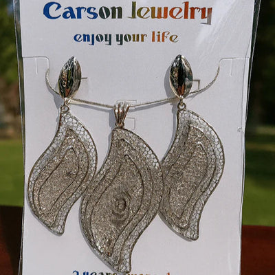 Pair of silver earrings on a Carson Jewelry card with a blurred natural background