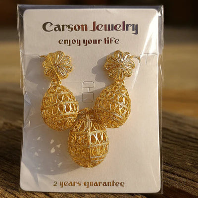 Gold earrings on a Carson Jewelry card with a blurred background