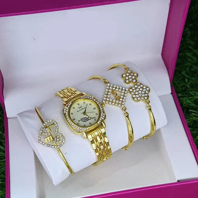 Gold watch and jewelry set in a pink box on grass